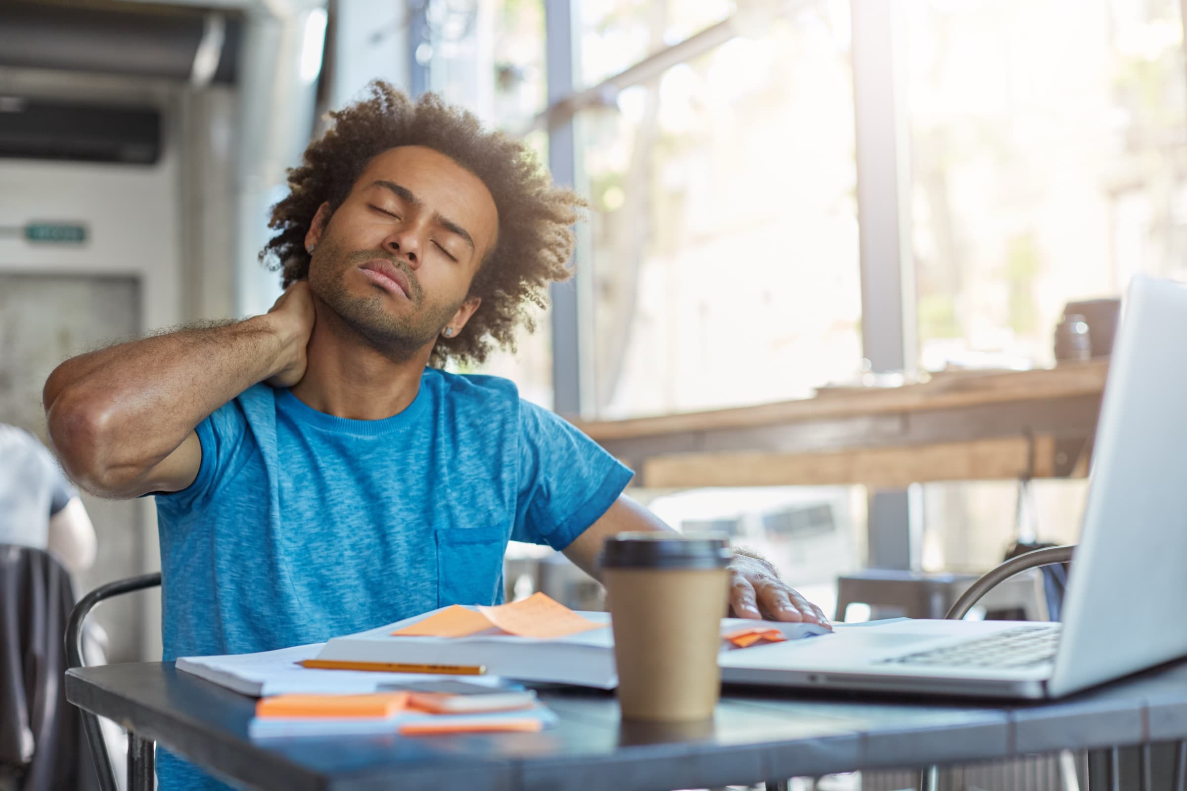 Man at a desk holding his neck in pain
