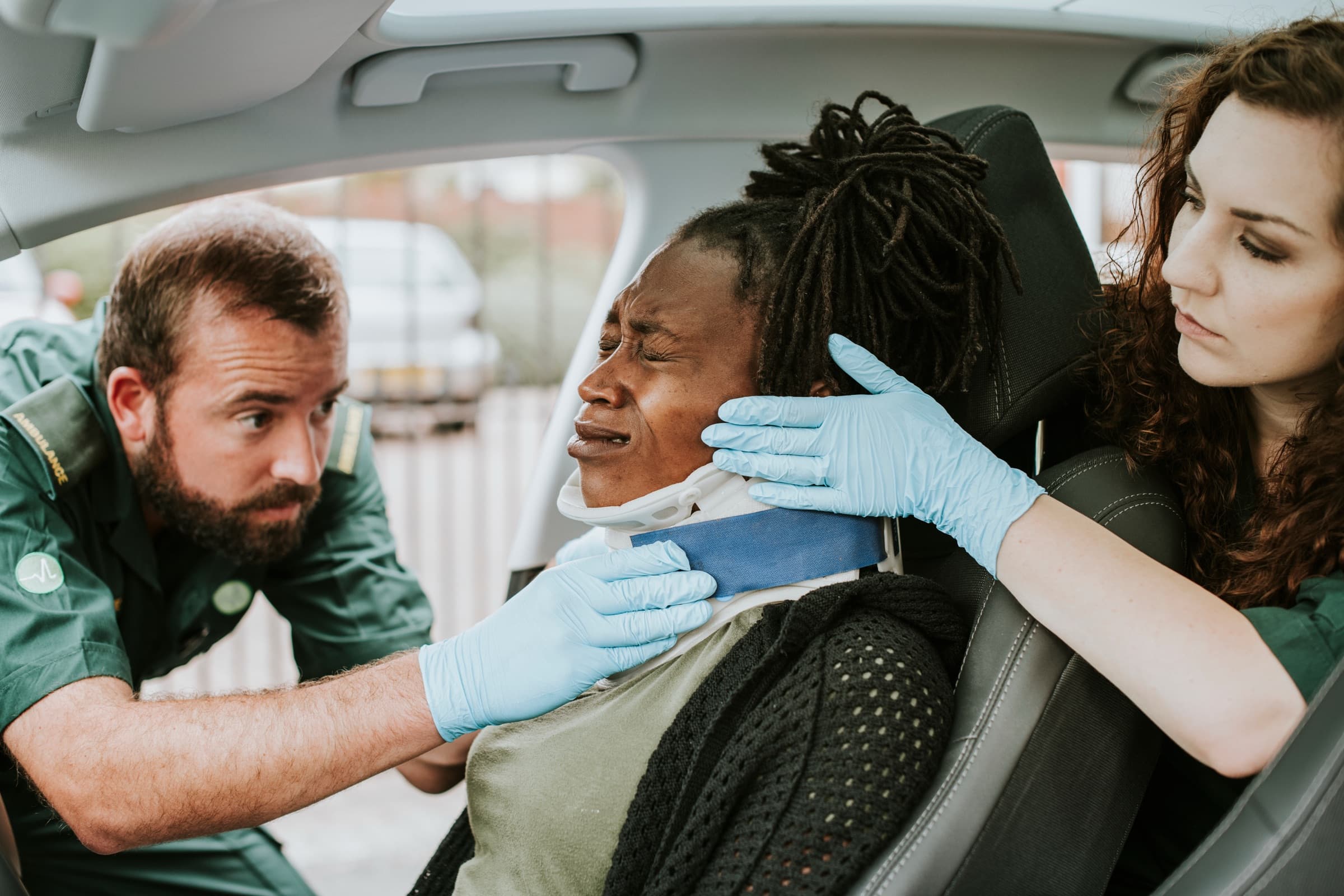 Paramedics fitting a neck brace on a woman after a car accident