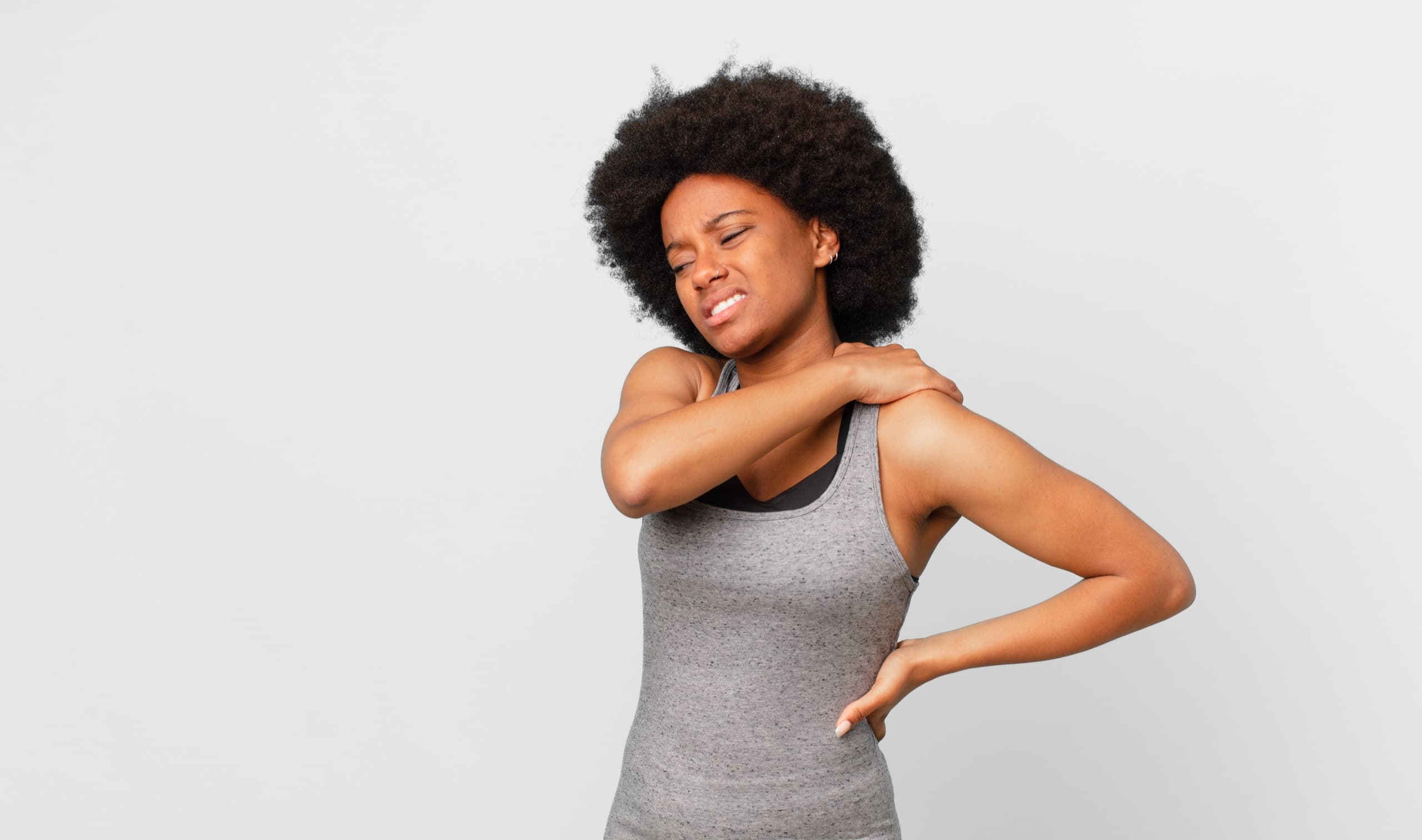 Woman holding her shoulder and lower back in pain